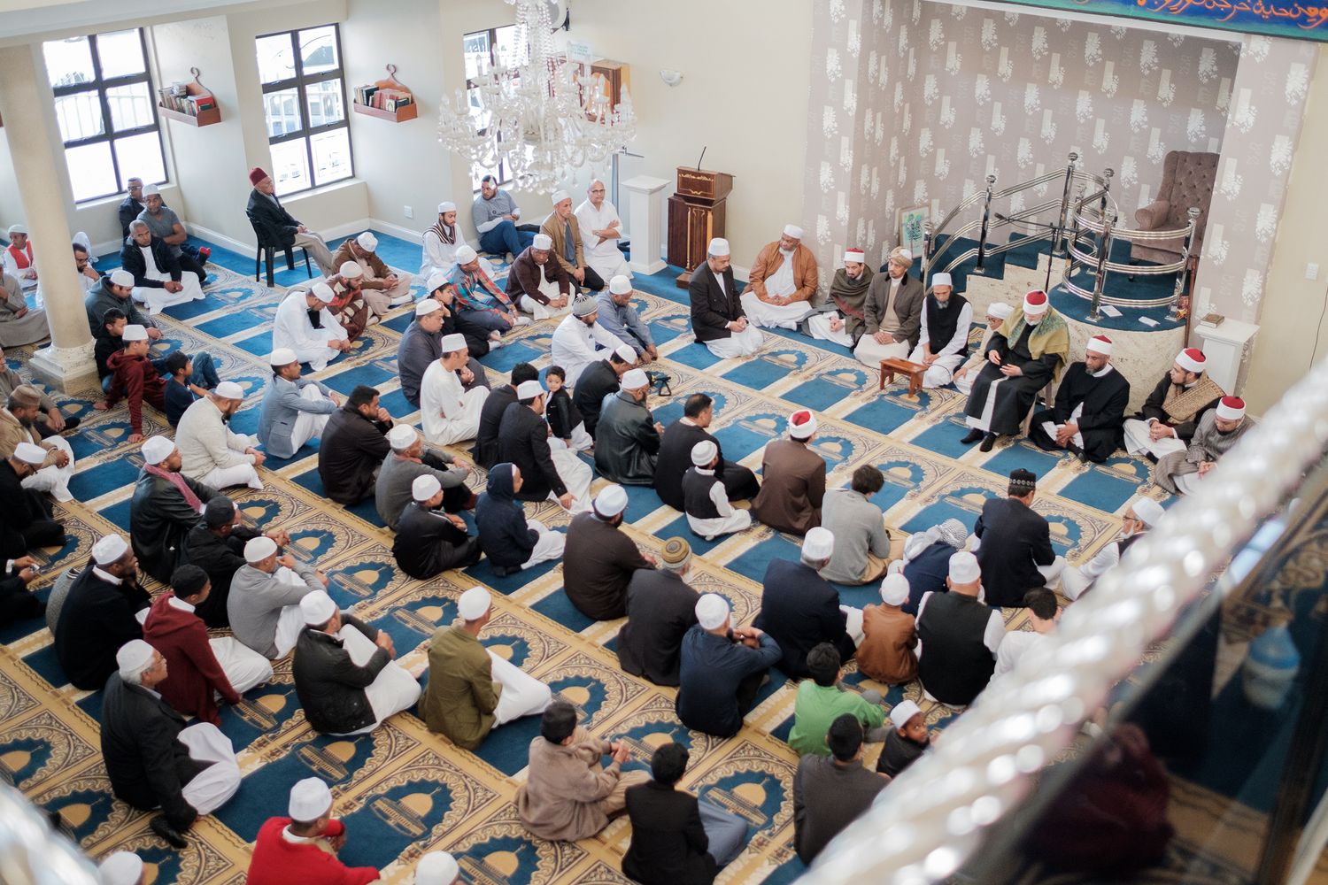 Overhead view of worshippers gathering in a mosque during prayer time.