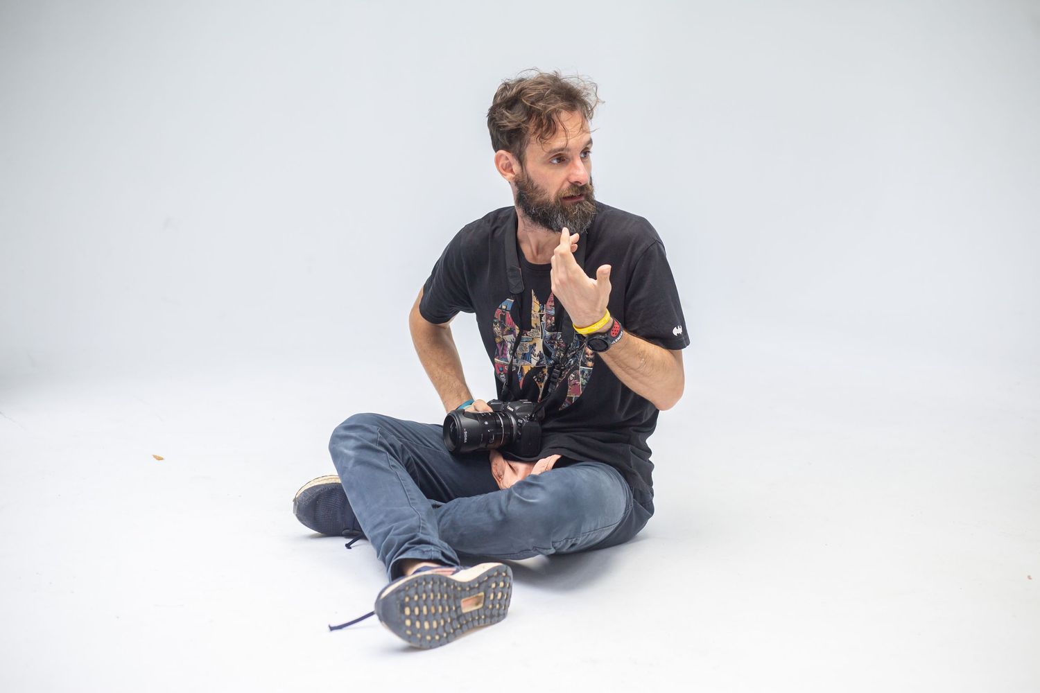 Fotógrafo creativo sosteniendo una cámara, contemplando ideas en un estudio luminoso y minimalista, listo para inspirarse.