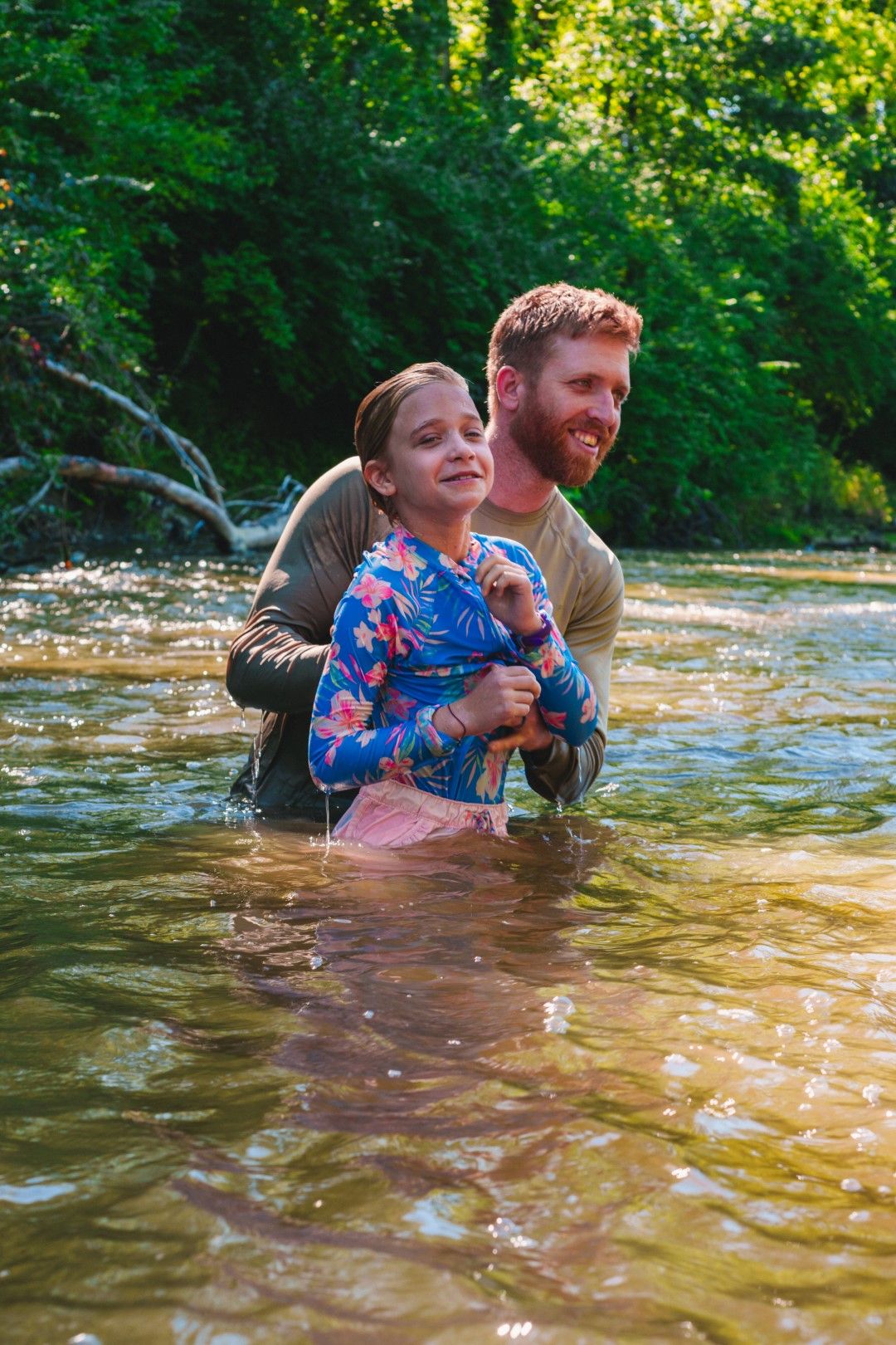 A joyful moment of parent and child playing together in a sunlit stream during summer.