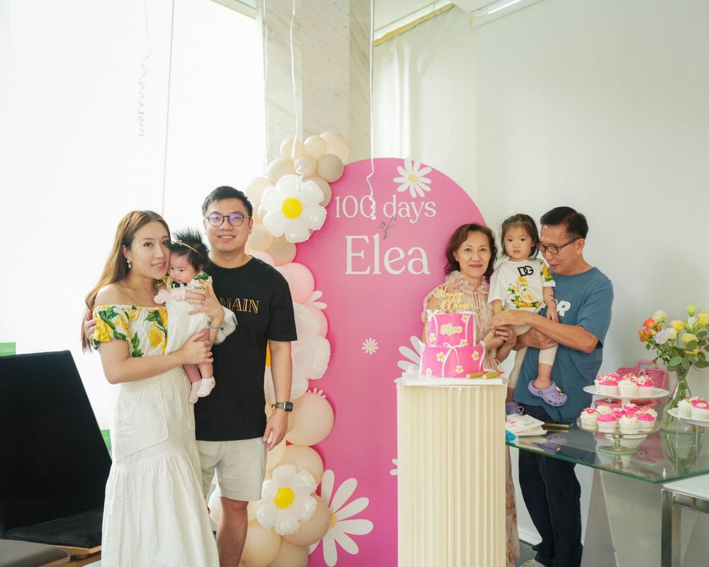 Party scene with pink floral backdrop and celebratory decor for a 100 days celebration.