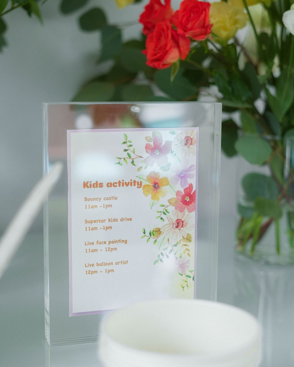 Kids activity schedule card displayed with floral decorations and a candle.