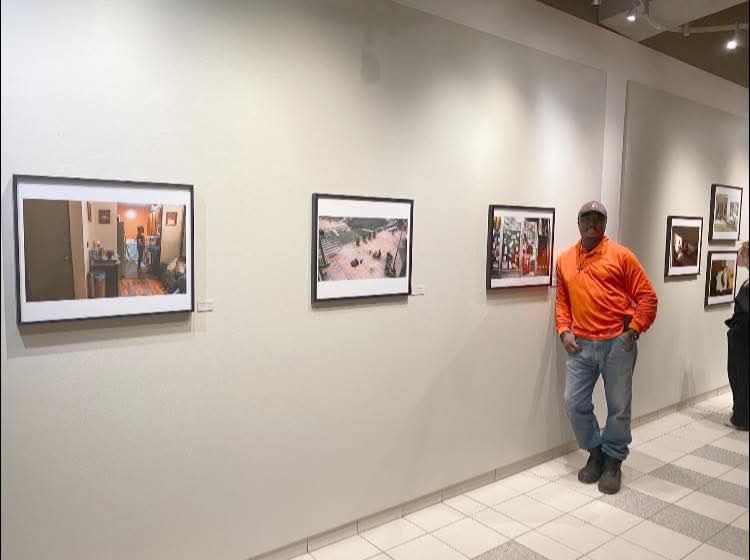 Art gallery exhibition showing framed photographs mounted on a white wall.