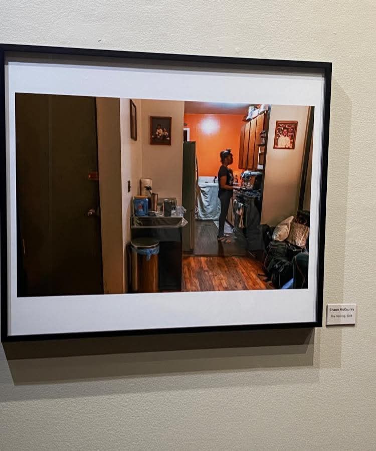 Black and white photograph of an interior hallway scene displayed in a gallery.
