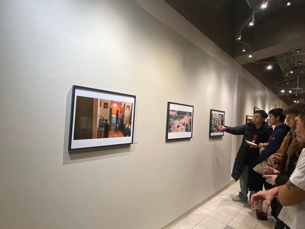 Gallery visitors viewing photography exhibition mounted on white walls.