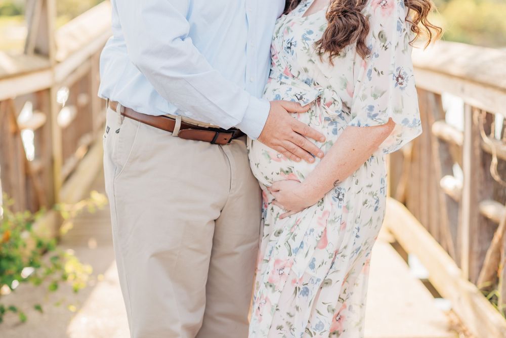 A close up image of a pregnant woman's belly while her husband holds her belly.