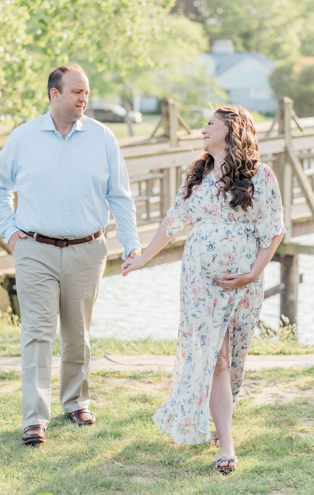 A young couple walks away from a bridge lakeside.