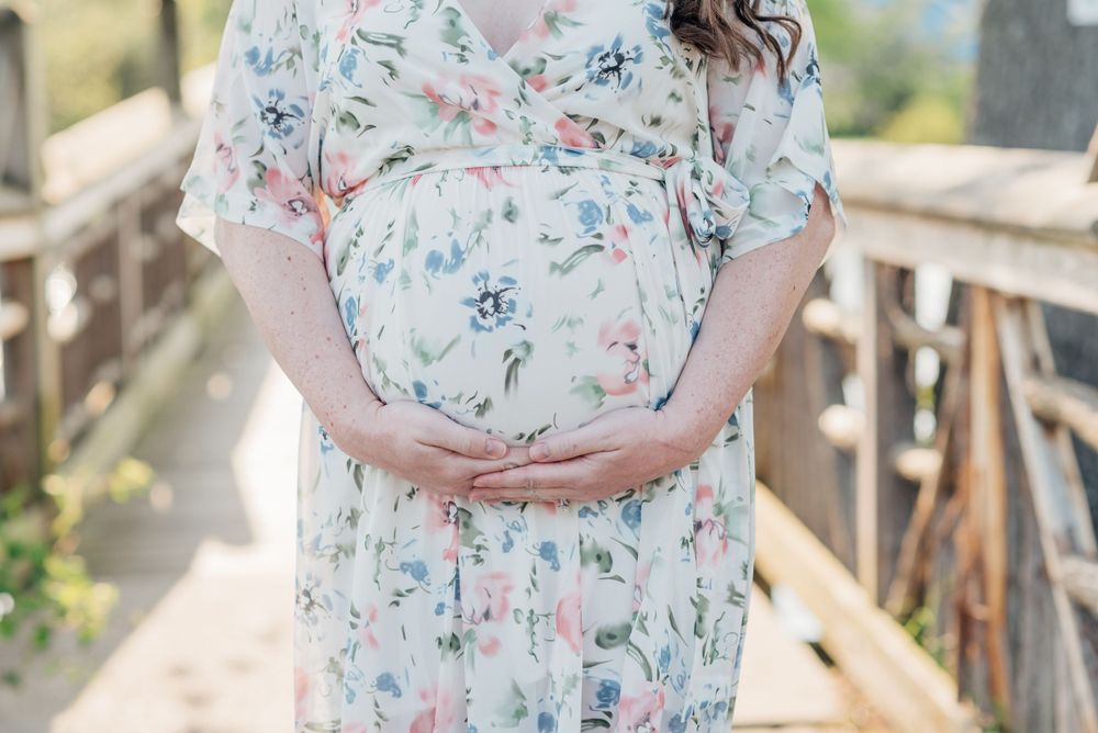 A close image of a pregnant woman's belly with her hands wrapping around her unborn child.