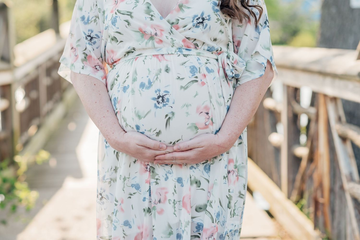 A close image of a pregnant woman's belly with her hands wrapping around her unborn child.