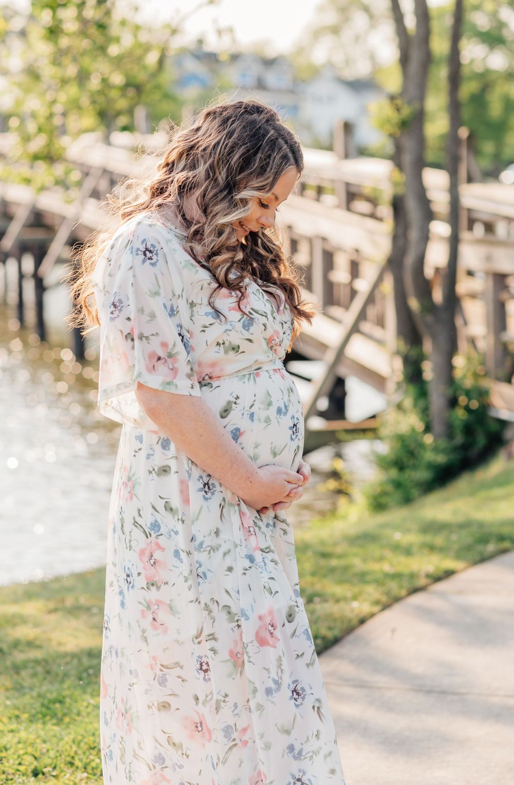 A pregnant woman looks down at her belly smiling.