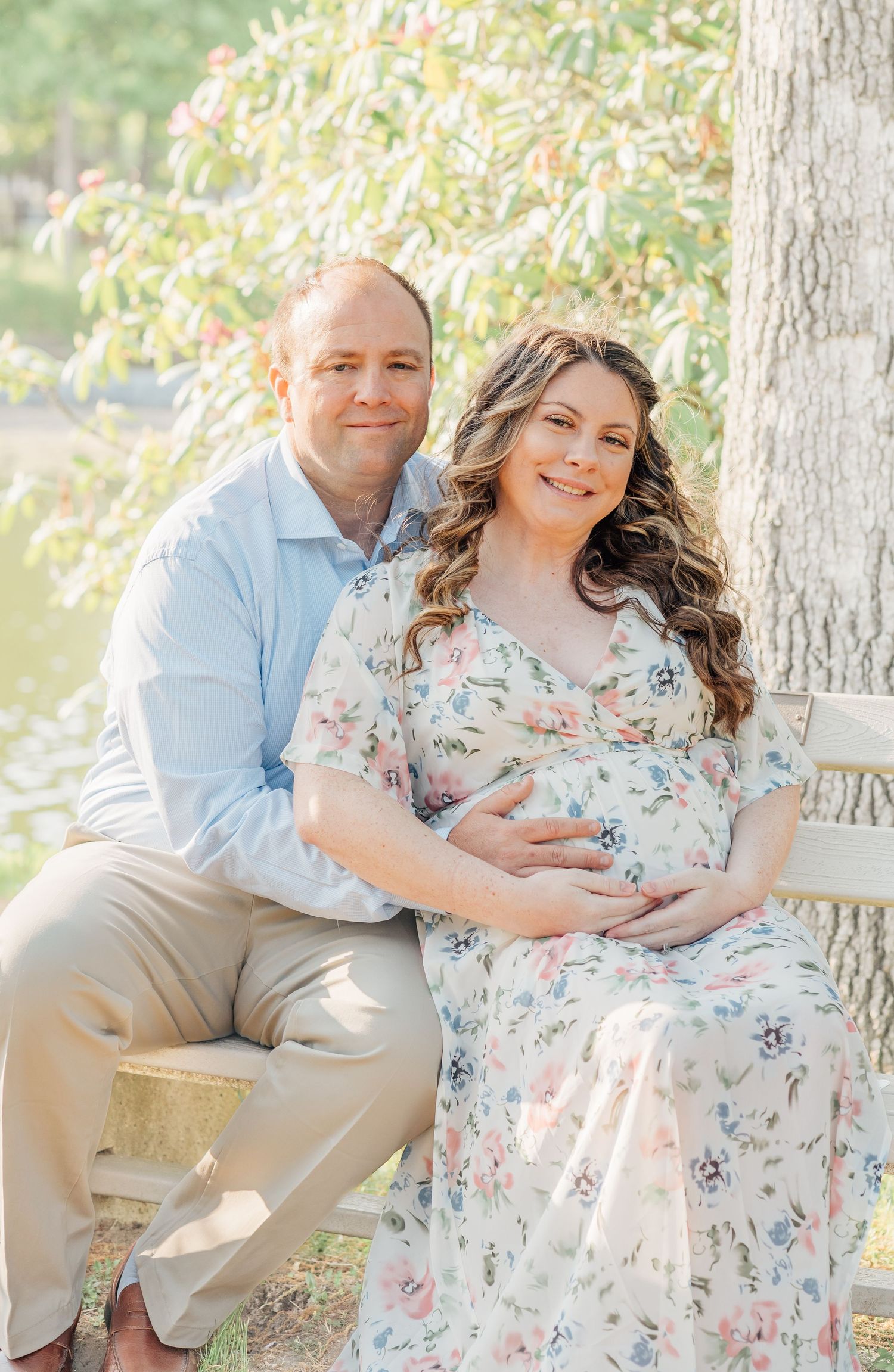 A couple sit on a bench in a New Jersey park smiling while a photo is taken of them.