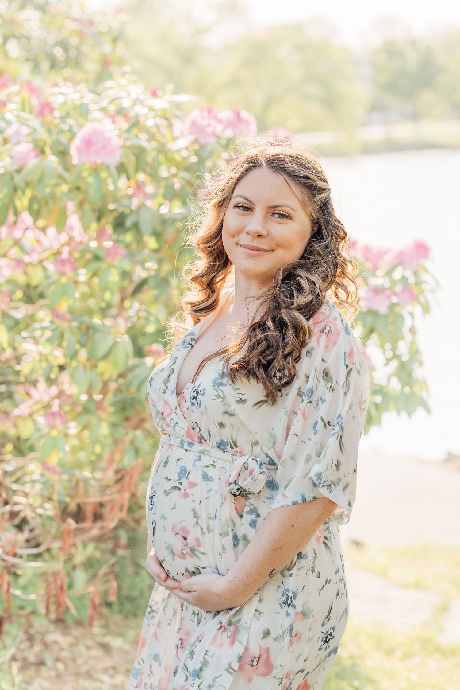 Maternity session with a pregnant woman in a white floral dress and curls in her brown hair.