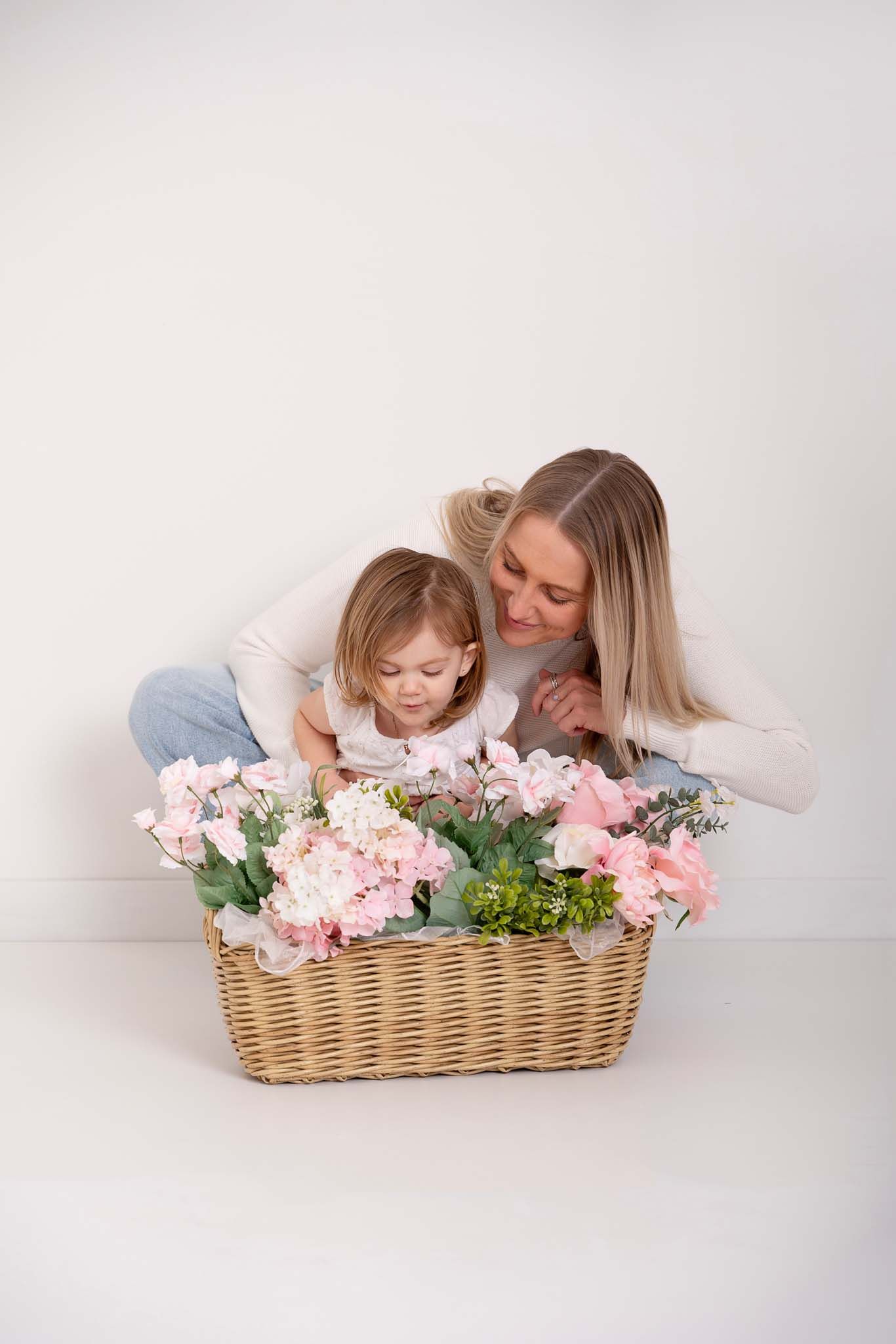 Mom and daughter pose naturally together with spring flowers wearing neutral modern clothing