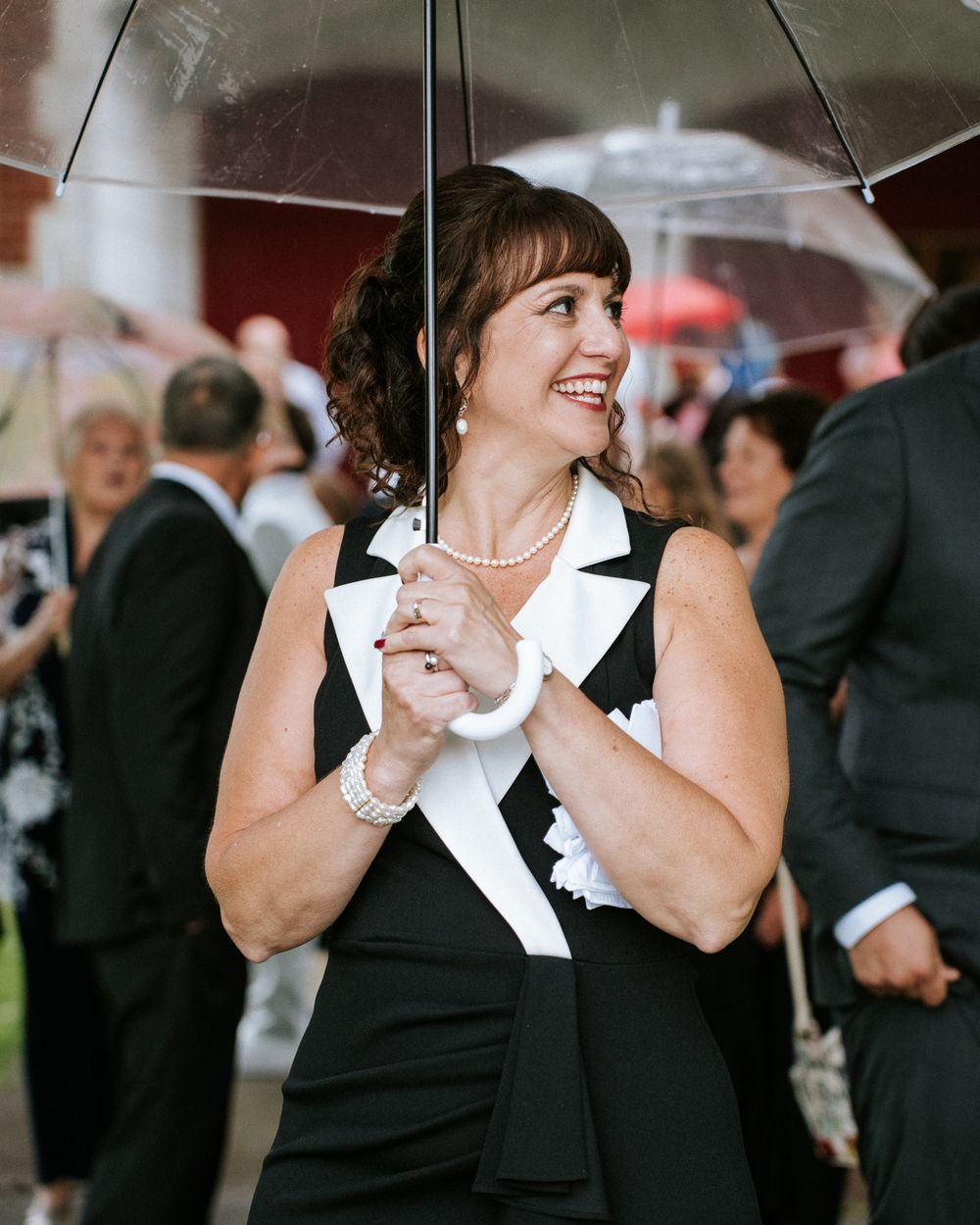 Des invités en robes noires à cols blancs dansent et rient pendant la célébration.