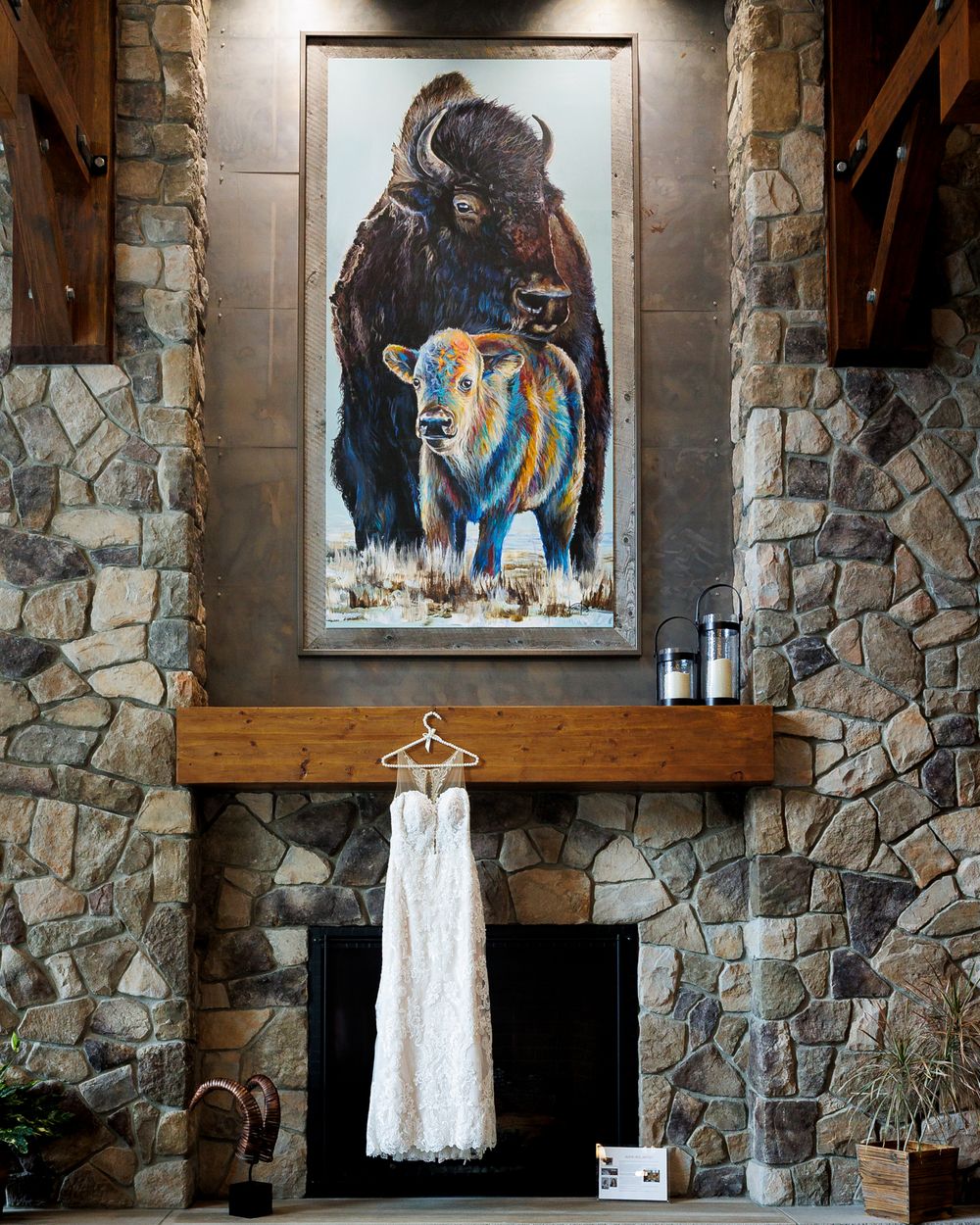 Wedding dress hanging on a stone fireplace mantle before the ceremony at Cambium Place