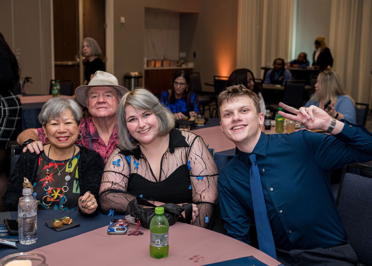 A group sits together at a round table during an event with drinks and snacks.