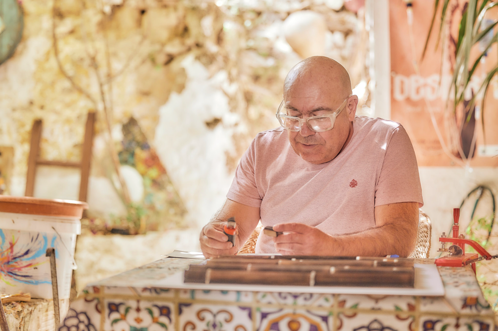 Person working with materials at sunlit outdoor table with natural lighting.