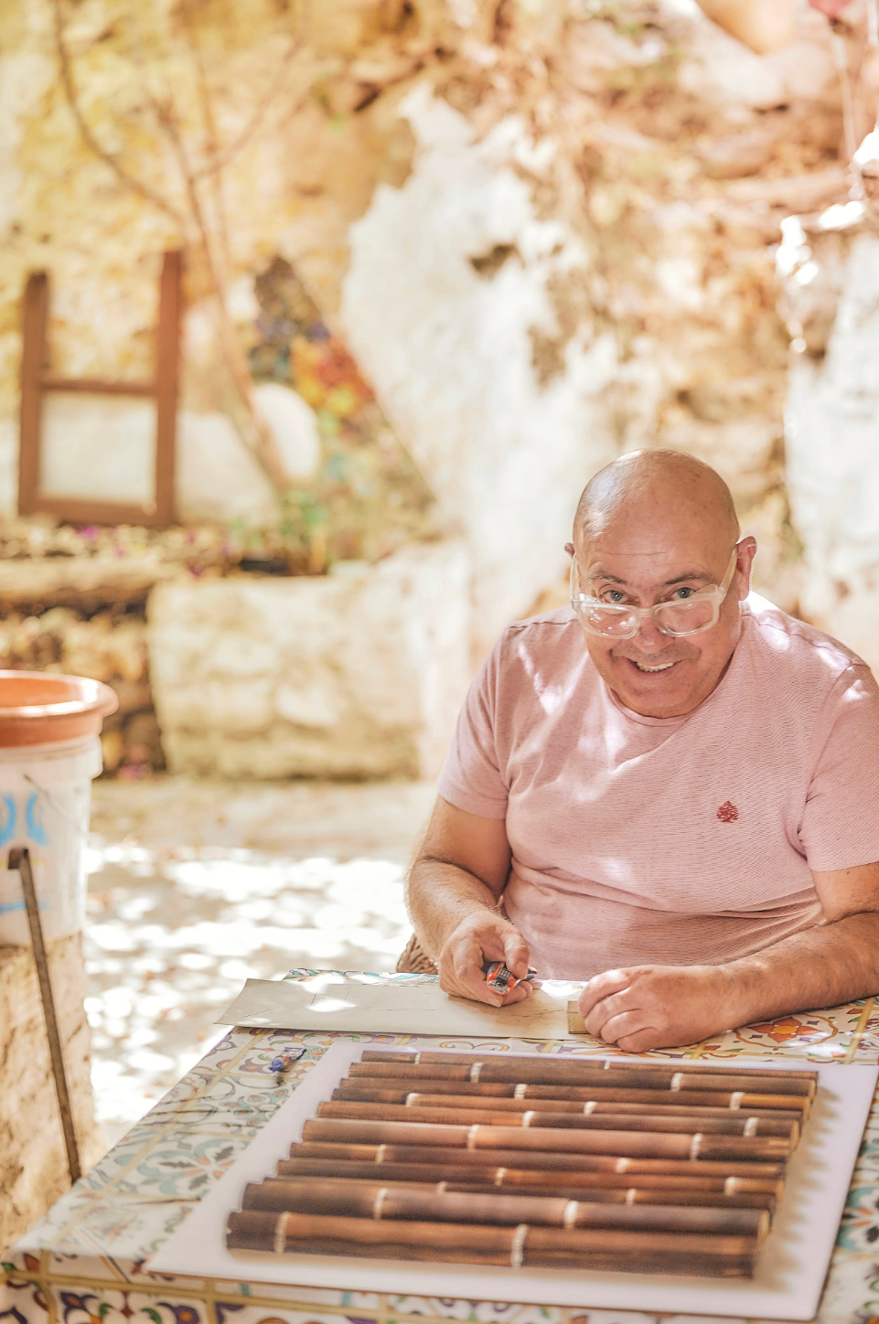 Person in pink shirt examining and writing notes at outdoor table.