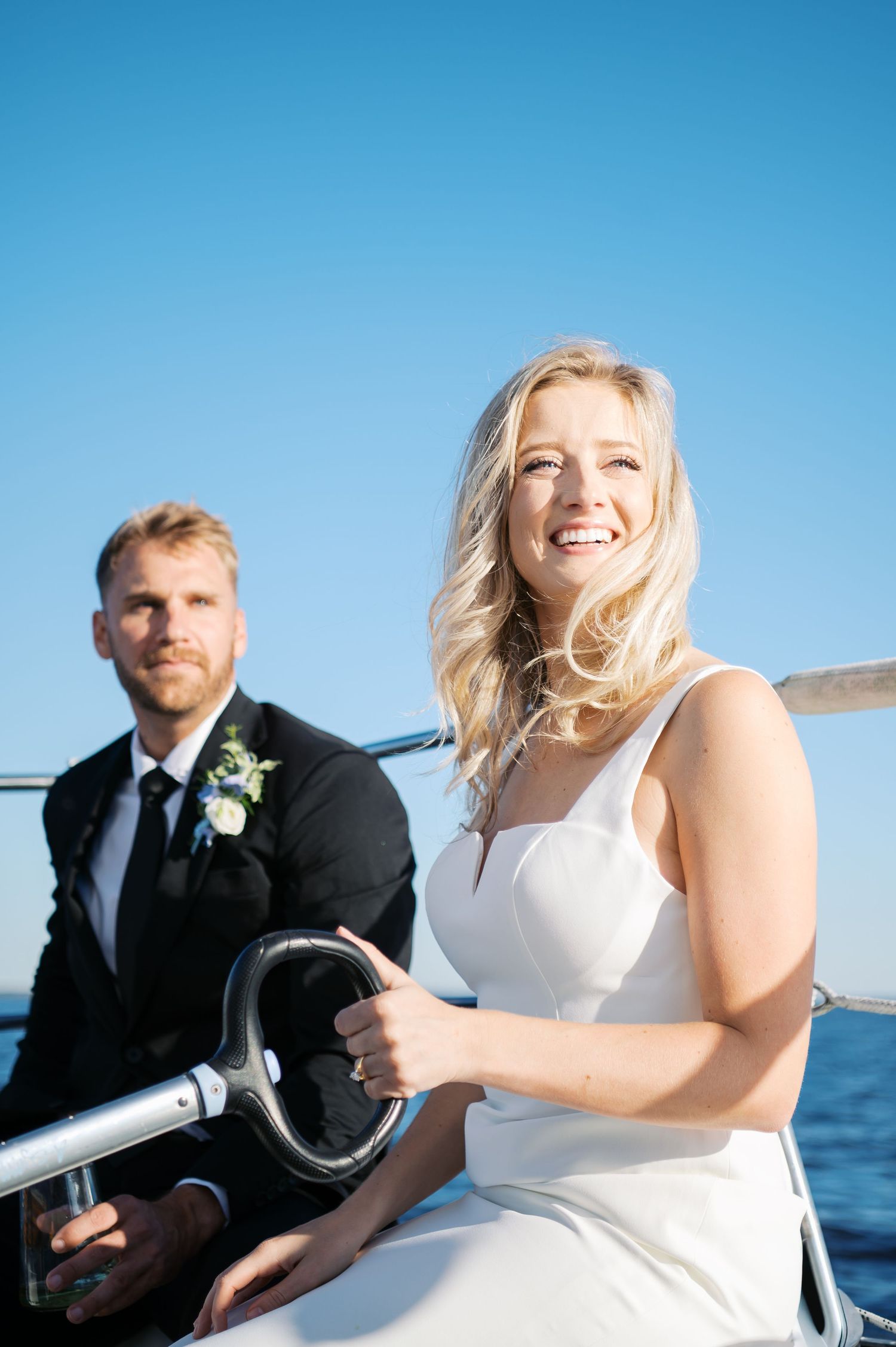 A bride driving a sailboat in a wedding dress. Photo by Heather Moss Photo. A Wilmington Wedding Photorapher.