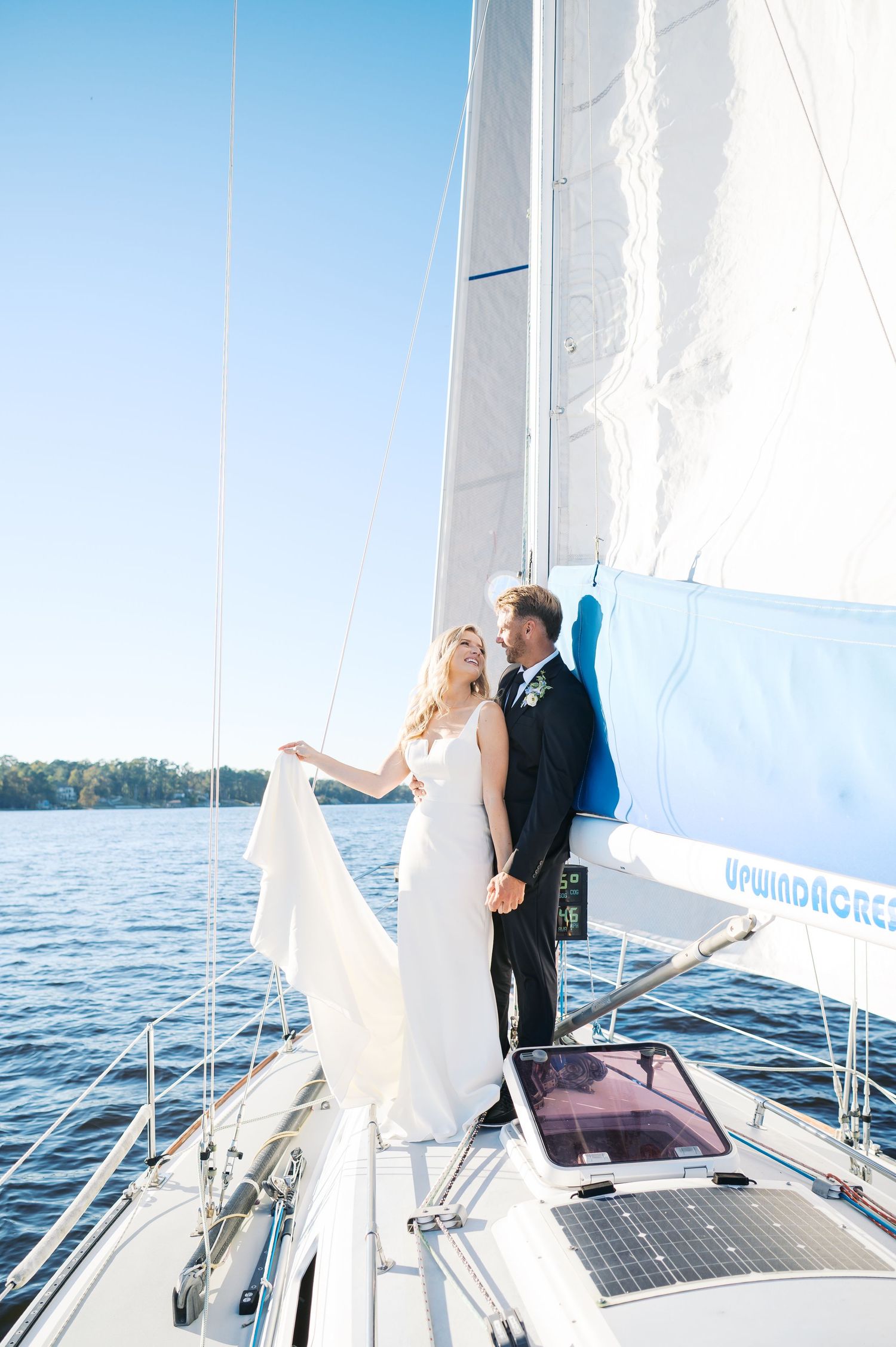A romantic wedding couple shares intimate moments while sailing on a yacht across blue waters. New Bern NC Wedding Photographer