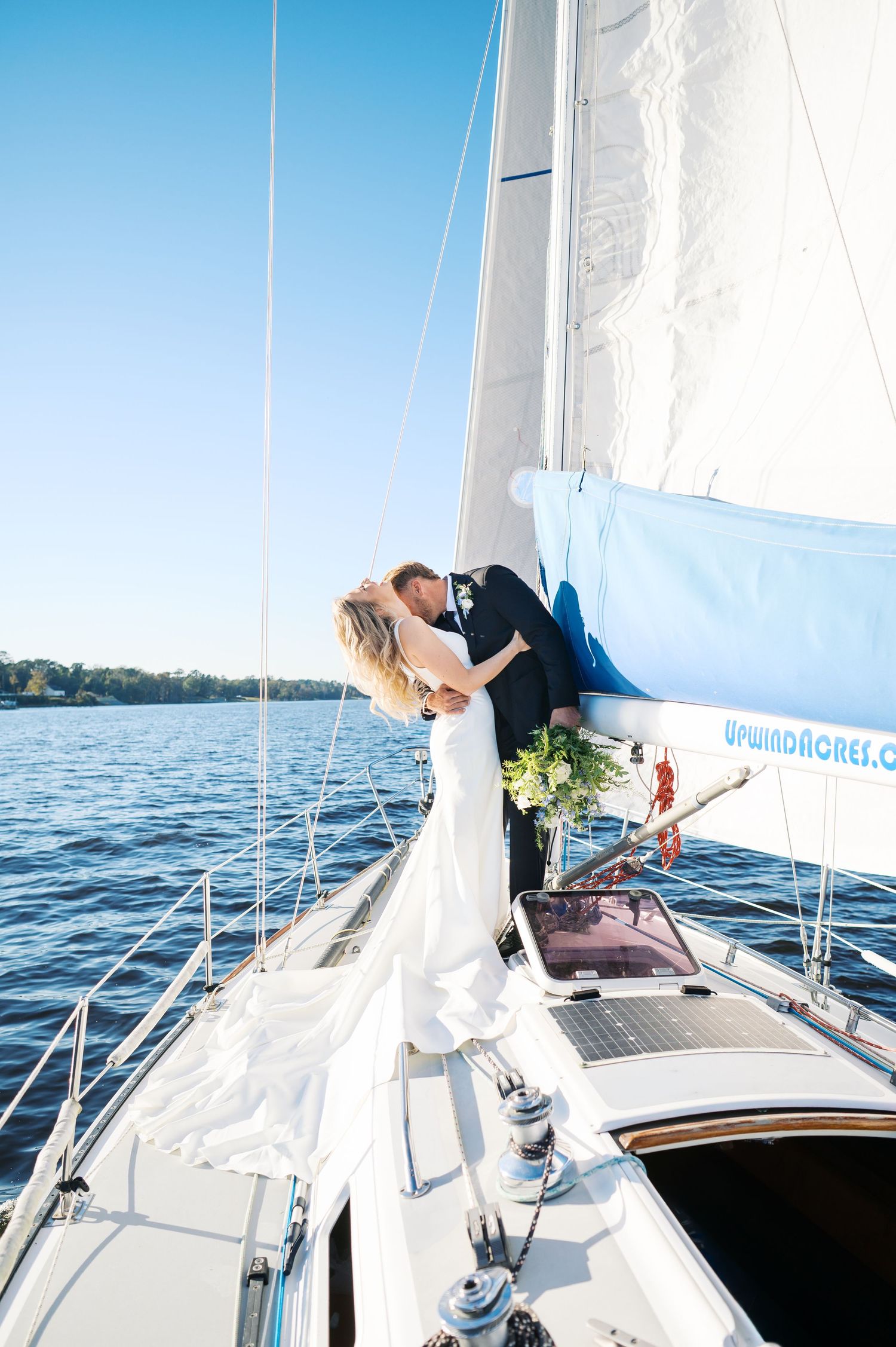 A newlywed couple embraces on the deck of a sailboat during their nautical wedding celebration. Photo by Heather Moss Photo