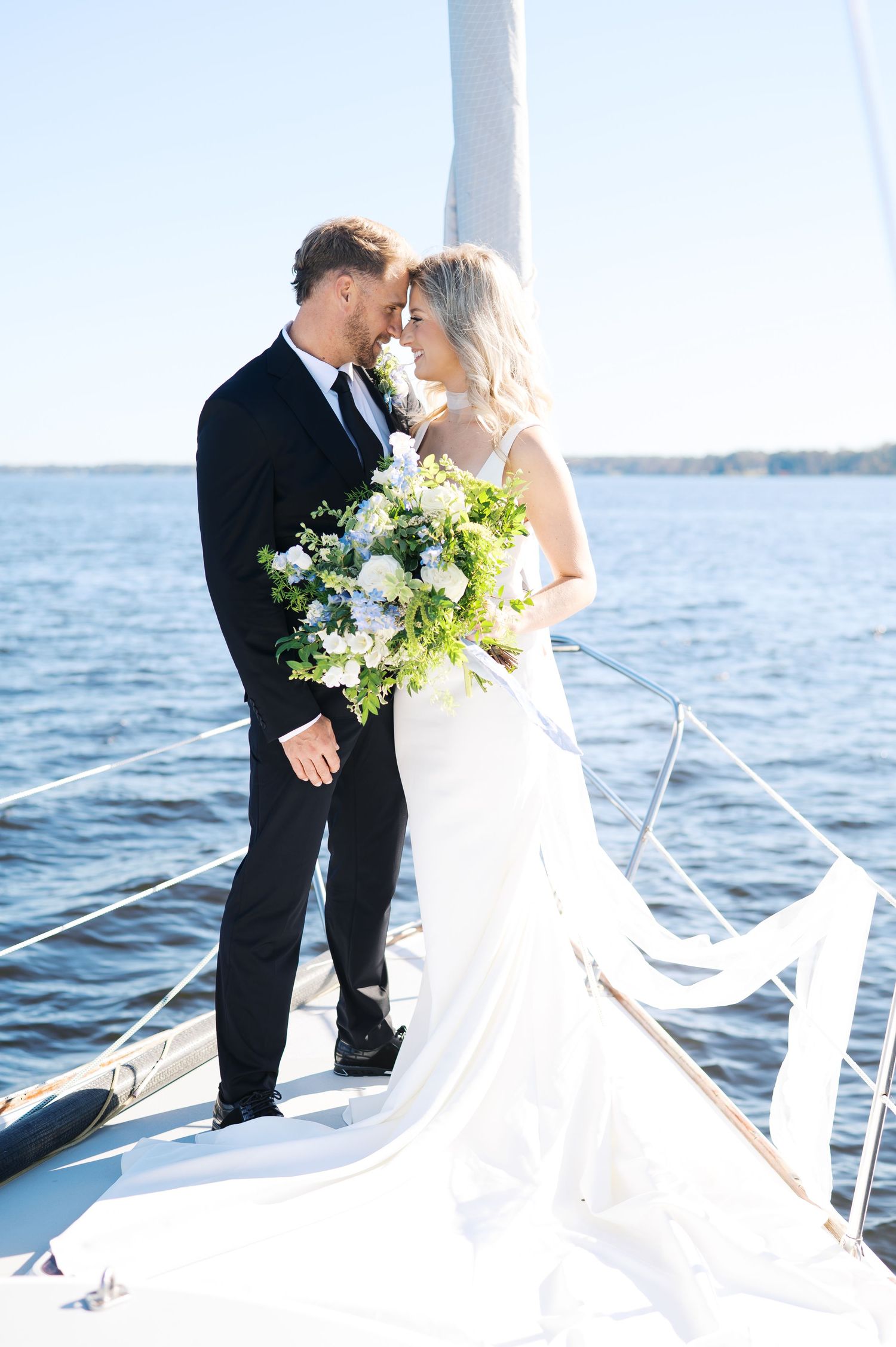 A romantic wedding photoshoot on a sailboat with the ocean and blue sky as backdrop. Coastal NC wedding photography