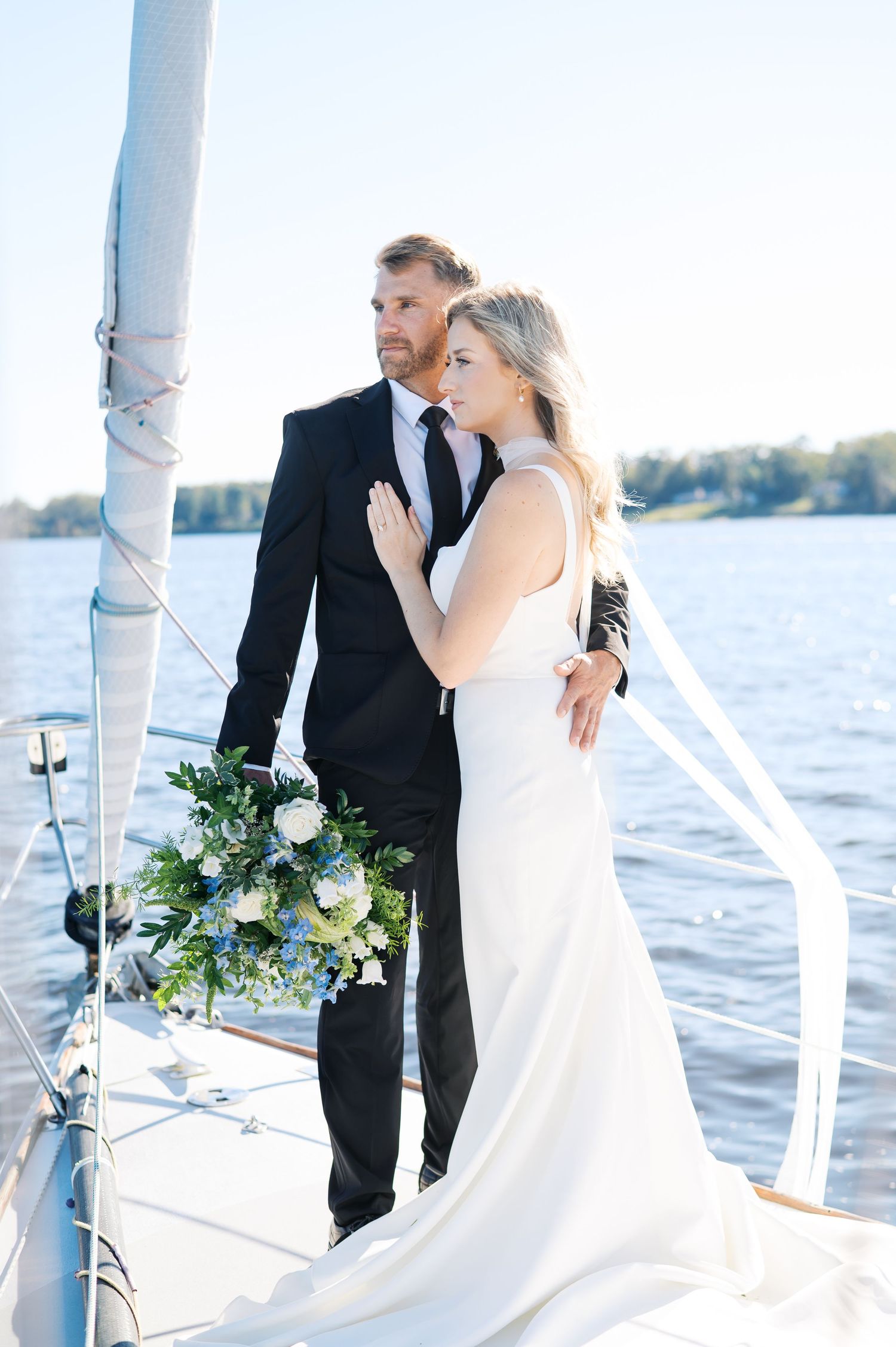 A romantic wedding couple shares intimate moments on a sailboat with water and white pillars in the background. New Bern Photographer
