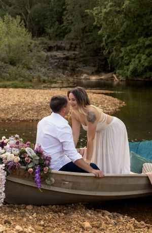 Couple shares romantic moment in canoe decorated with purple and pink flowers.