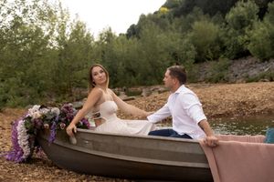 Floral decorated canoe sits on rocky shore during romantic photoshoot.