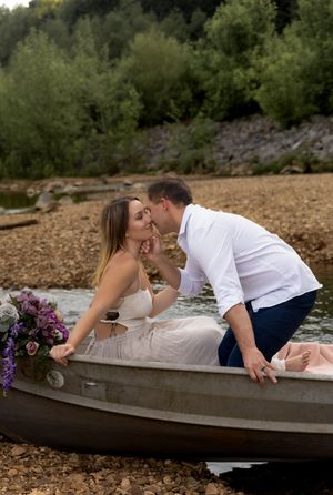 Romantic couple poses in canoe decorated with flowers during lakeside photoshoot.