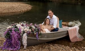 Scenic lakeside photo with decorated canoe and couple in romantic pose.