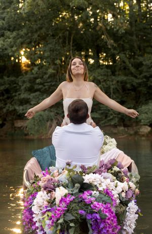 Dreamy lakeside photoshoot with boat adorned in purple and white blooms at golden hour.