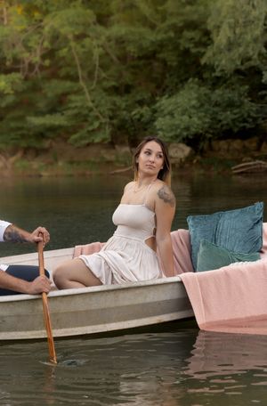 A romantic scene on a boat with a pink blanket at sunset by a tranquil lake.