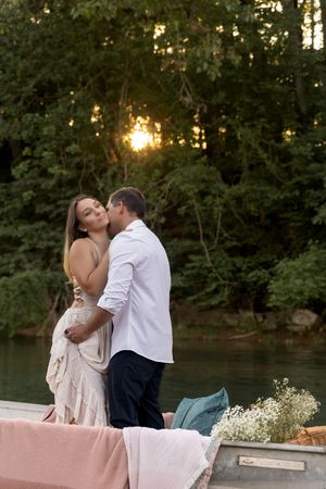 Tender moment captured between a couple on a boat with baby's breath flowers at dusk.