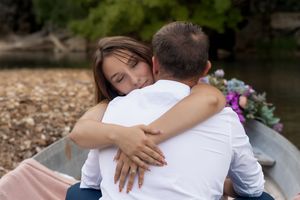 Intimate moment captured of a couple hugging in a boat decorated with flowers and blankets.