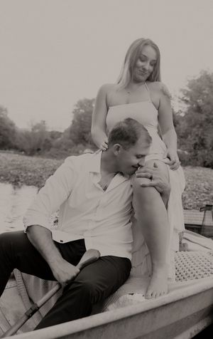 Black and white photo of a couple sharing an intimate moment in a rustic rowboat.