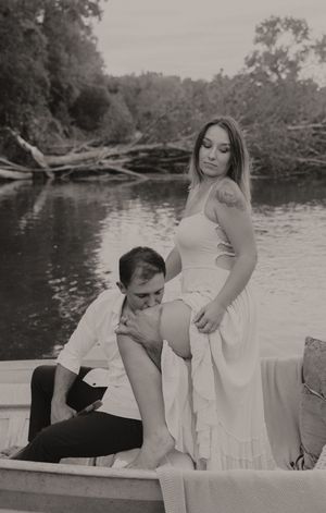 Artistic black and white photo of a couple sharing a romantic moment in a boat on a river.