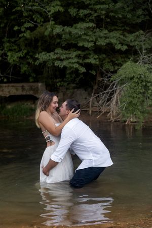 Couple wades into lake water during romantic photoshoot.