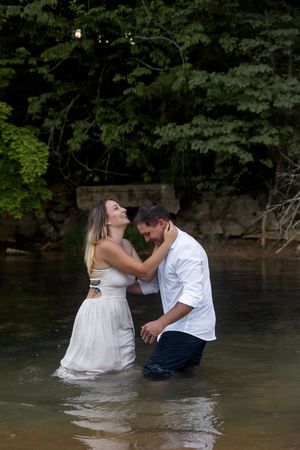 Couple shares joyful moment while standing in lake water.