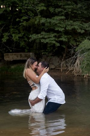 Couple shares passionate kiss during water photoshoot in lake.