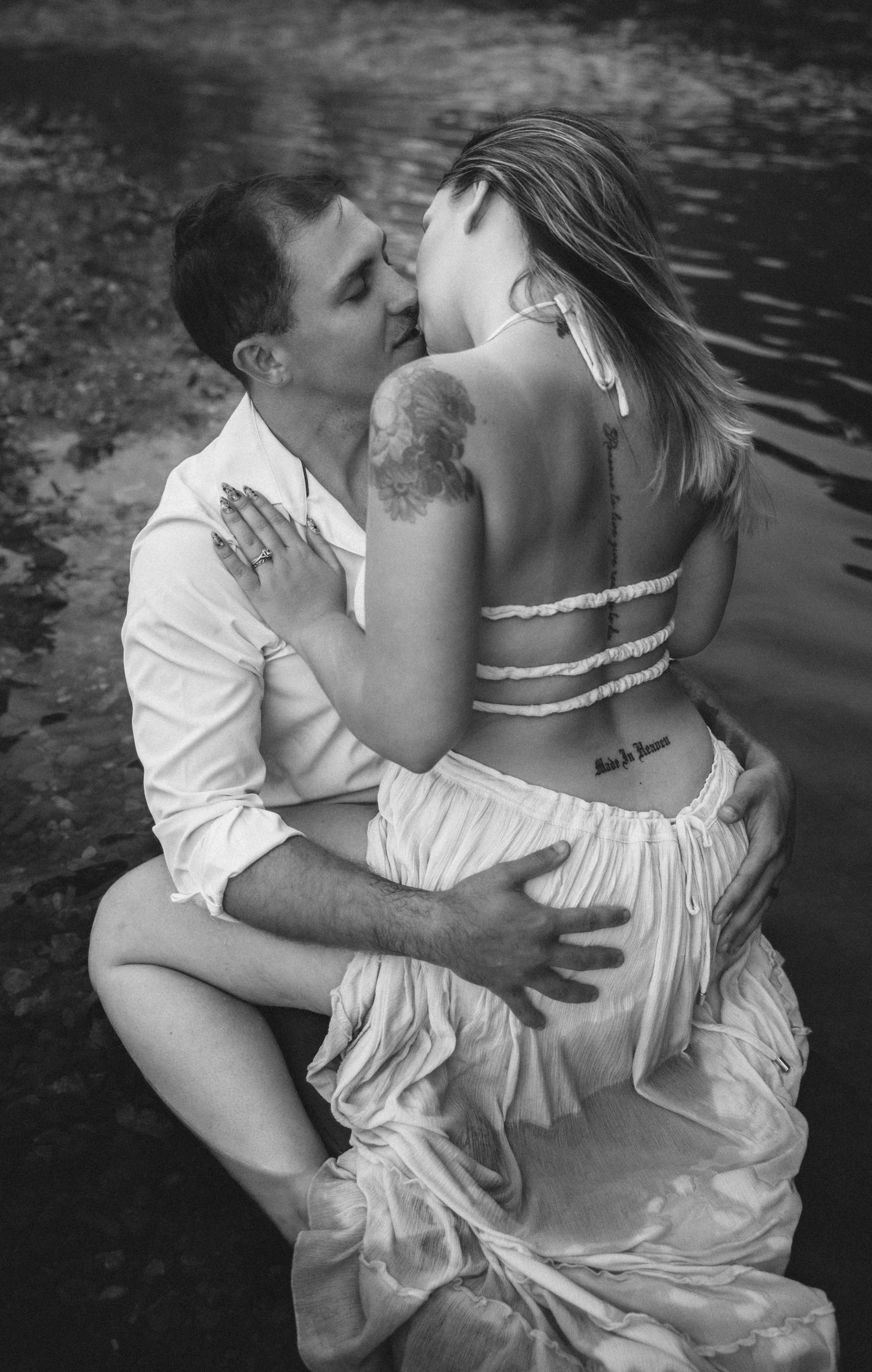 Romantic black and white photos of couple embracing by water's edge.