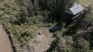 Aerial panoramic view of a mountainside landscape with trees and buildings.