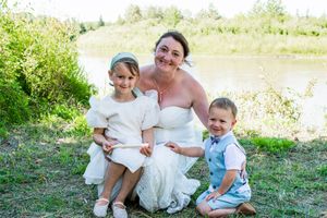 Family members gather for casual outdoor wedding photos near a lake with natural landscaping.