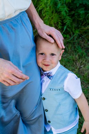 Young child in light blue vest and bowtie at outdoor wedding.