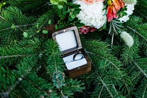 Wedding rings and jewelry displayed on evergreen branches with floral decorations.