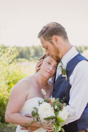 Intimate wedding portrait with couple sharing tender moment outdoors.