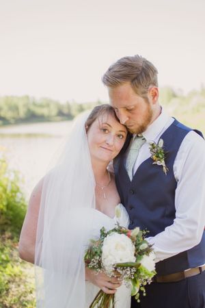 Romantic wedding portraits captured in soft lighting with natural bouquets and a waterfront backdrop.
