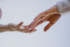 Close-up of hands showing wedding rings against white background.