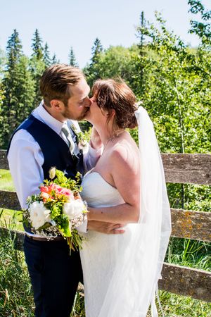 Romantic wedding couple embracing in garden setting with summer flowers.