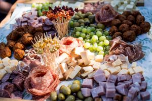 An elegant charcuterie board display featuring meats, cheeses, olives and fruits at a wedding reception.