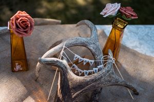 Wedding decor details featuring pink roses and vintage glass bottles with bunting decorations.